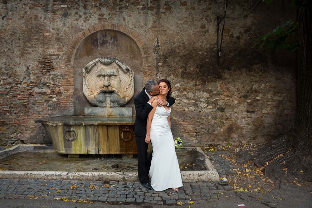 Bride and groom in front of the water fountain found at the entrance of the park.