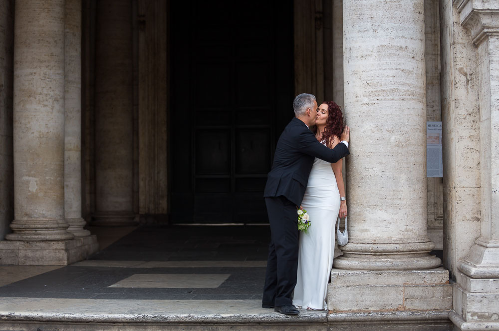 Newlyweds romantically kissing in a square.