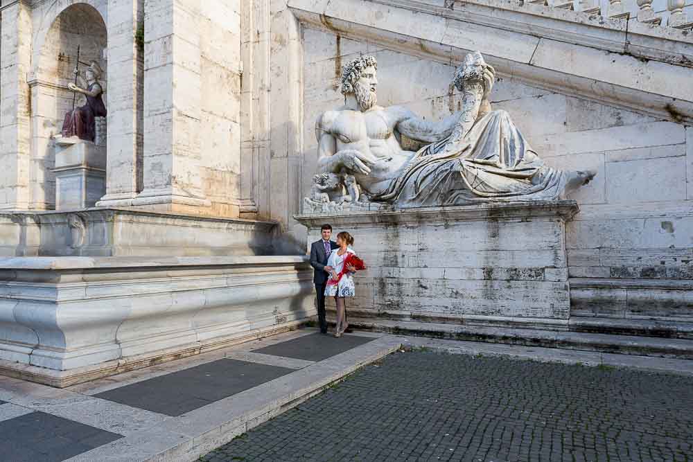 Image of a couple standing before an ancient statue in Piazza del Campidoglio.