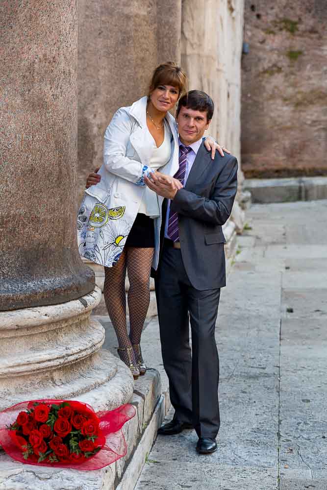 A couple posed next to a column.