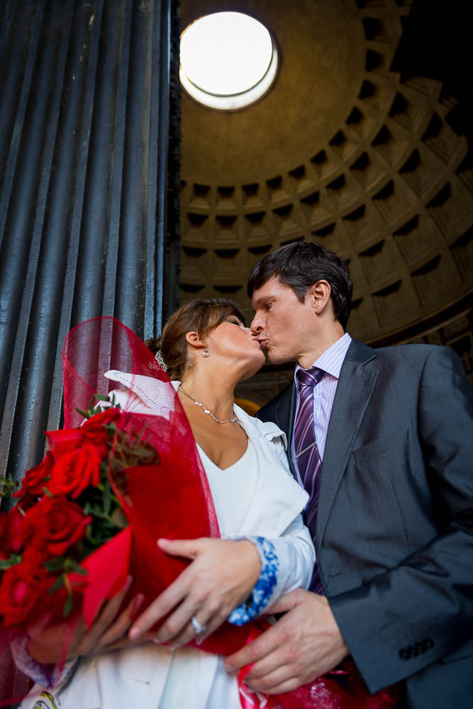 Kissing under the light of the Roman Pantheon during an engagement phototour.