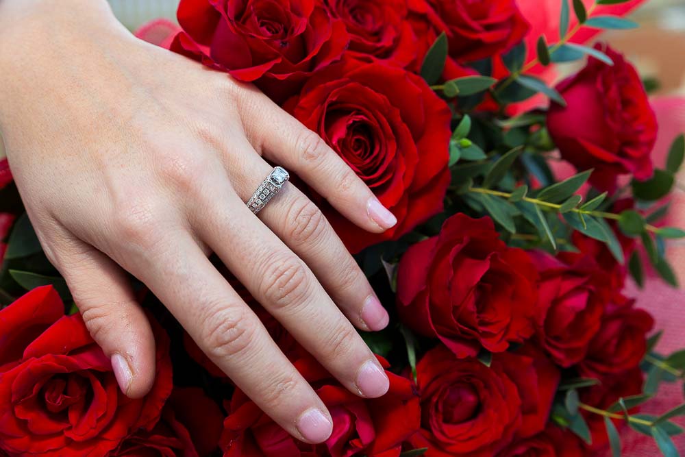 Engagement ring close up over red roses.