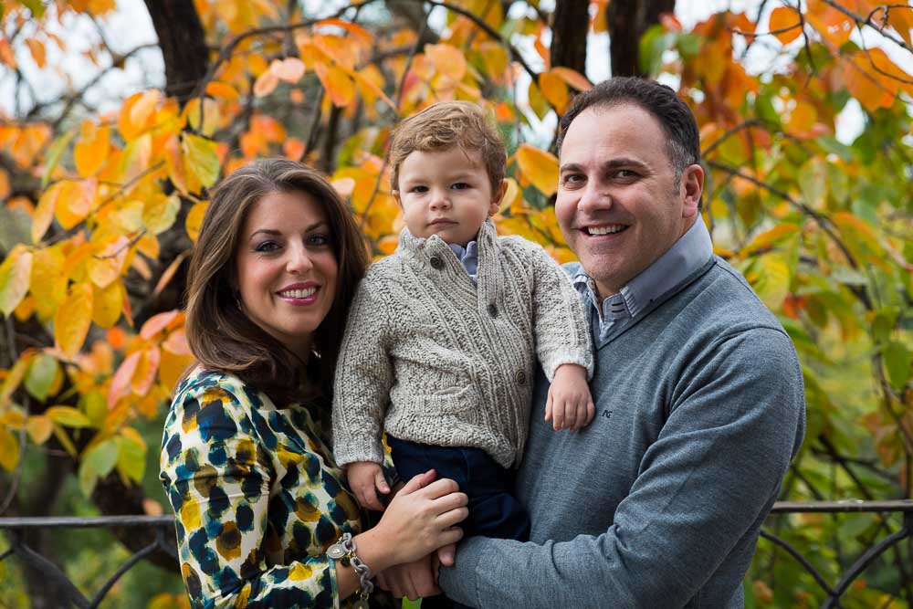 Family portrait photo session in the fall. Autumn tree in the background.