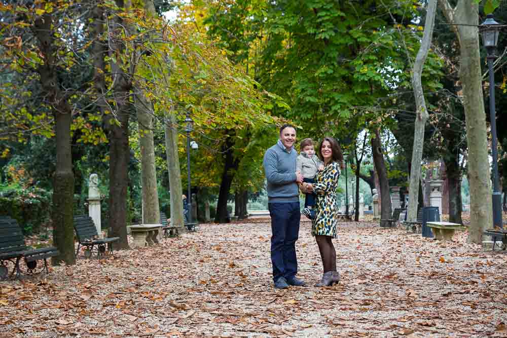 Park setting for a family shoot with trees on the sides and fallen leaves on the ground