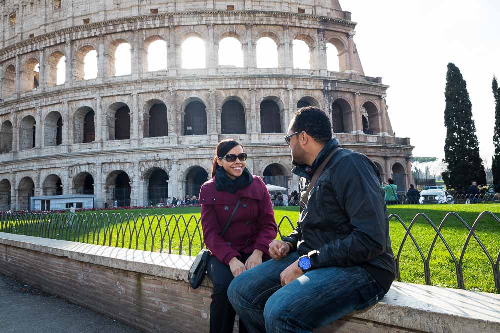 Couple sitting down before the view of the Roman Colosseum