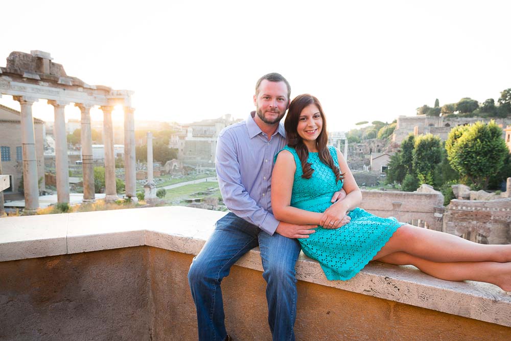 Couple sitting down on wall overlooking the ancient roman Forum. Photo Tour in Rome Italy. 